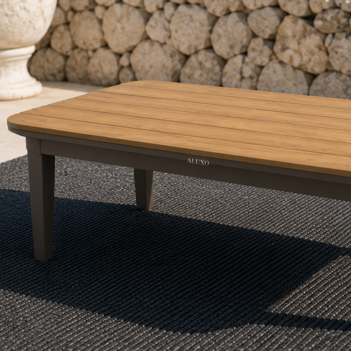 Light brown wooden slatted tabletop with dark grey sturdy legs on textured black rug.