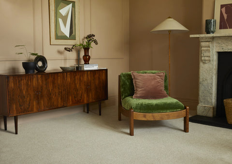 Saxony Venetian Marble carpet in lounge with green velvet chair, sideboard, and marble fireplace