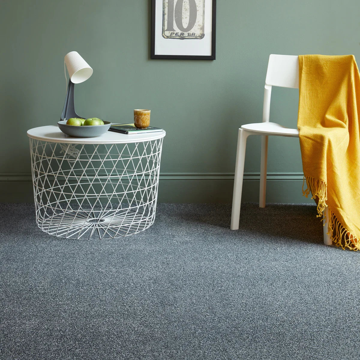 Saxony nimbus grey carpet with white chair, yellow throw, and modern side table