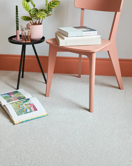 Light saxony carpet in modern room with blush chair, small black side table, and decor accents