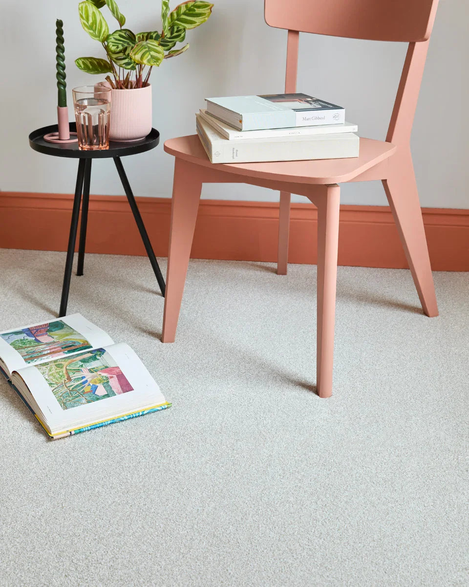 Light saxony carpet in modern room with blush chair, small black side table, and decor accents