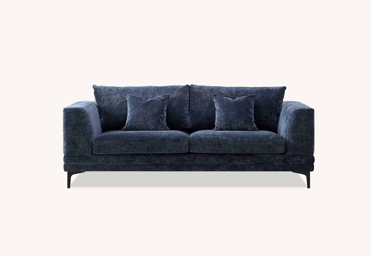 Blue velvet sofa with two matching scatter cushions and slim black legs, front view
