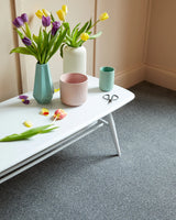 Grey textured carpet in a room with white table, vases, and colorful tulips