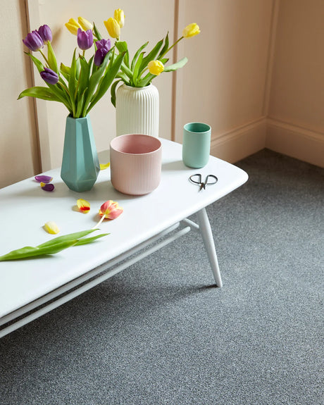 Grey textured carpet in a room with white table, vases, and colorful tulips