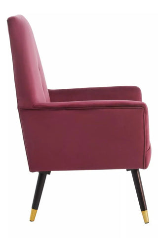 Wine velvet accent chair side view with tapered black legs and gold tips