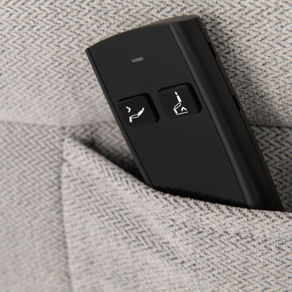 Close up of recliner sofa remote in textured grey fabric pocket