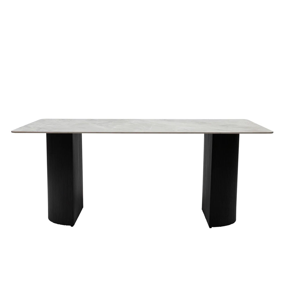 A modern rectangular dining table with a light gray stone or concrete-look top and two thick black pedestal legs, shown against a plain white background.