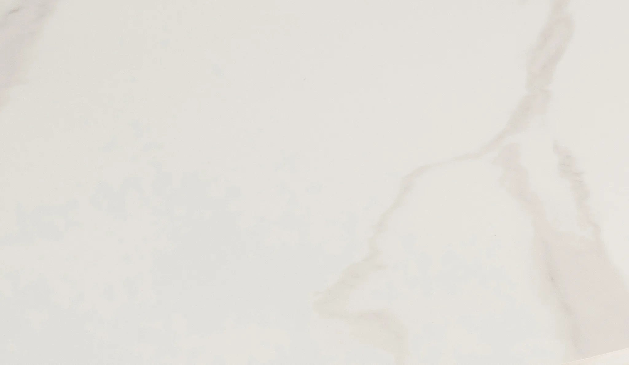 A close-up of a light warm off-white surface with soft gray and beige marble-like veining.