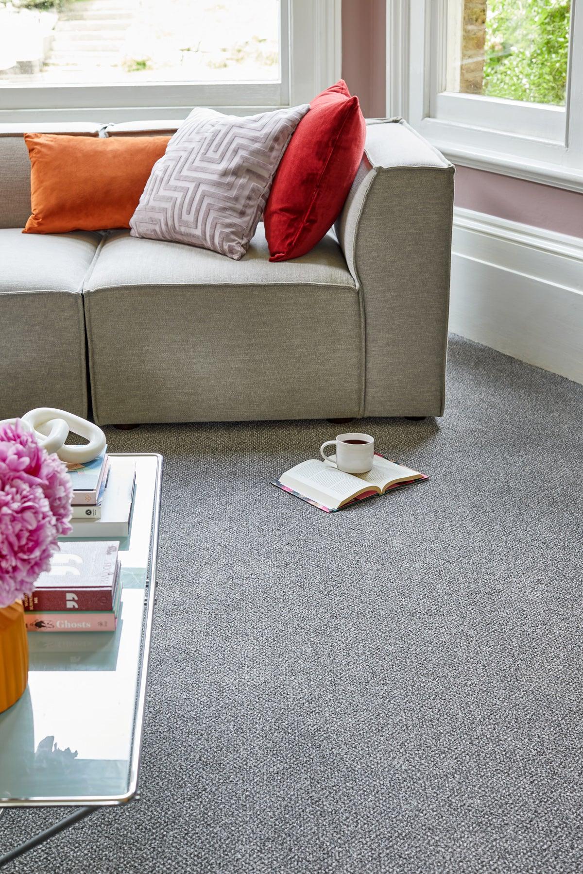 Grey carpet with subtle texture styled in a living room with a sofa and colourful cushions