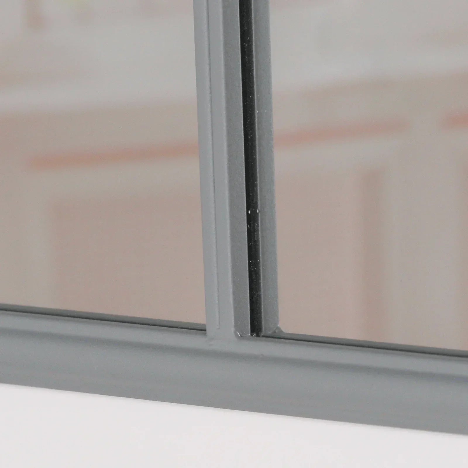 Close-up of grey metal mirror frame with intersecting bars and reflective glass surface