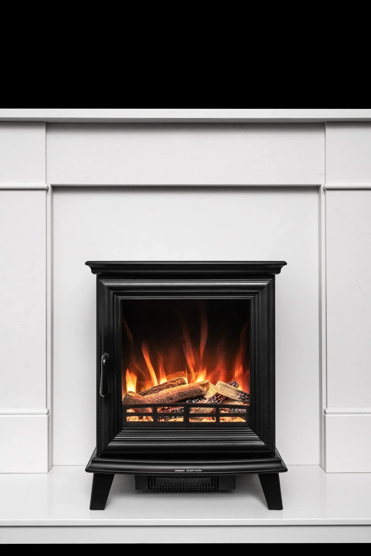 Black electric fireplace heater with log effect inside white fireplace surround