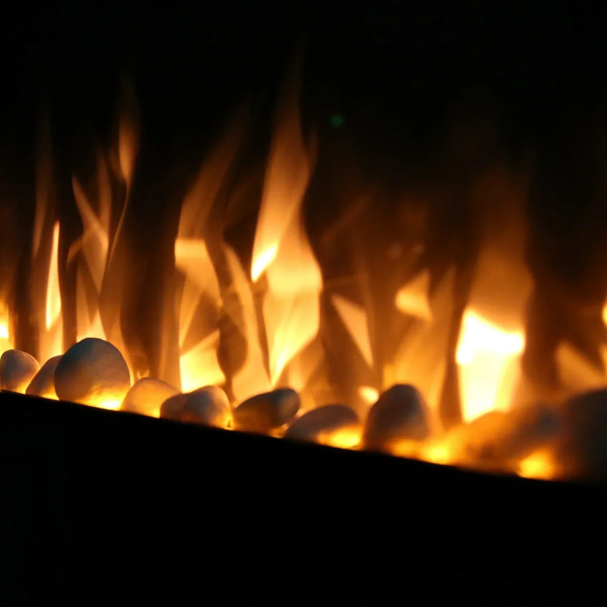 Modern electric fire with orange flames and white pebbles in close-up view