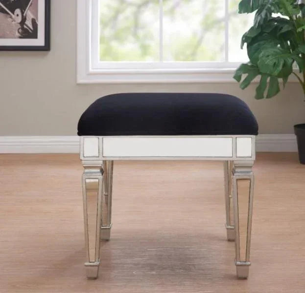 Mirrored vanity stool with black upholstered seat in bright room with wood flooring