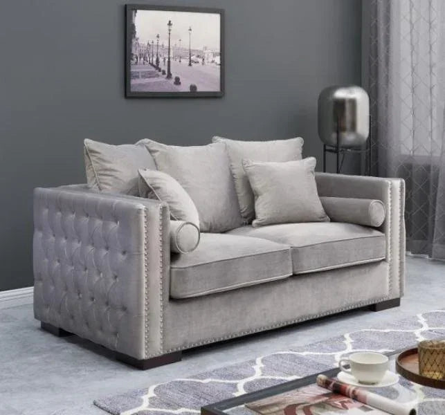 Grey velvet sofa with tufted arms and scatter cushions in modern living room