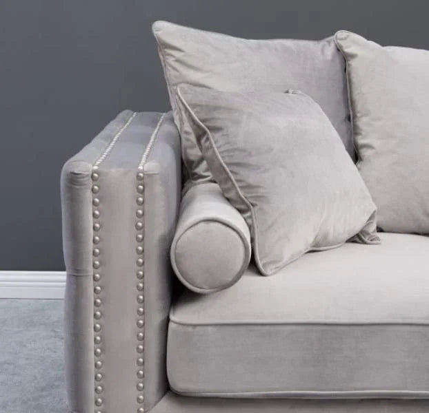 Light grey velvet sofa with studded armrest and matching scatter cushions