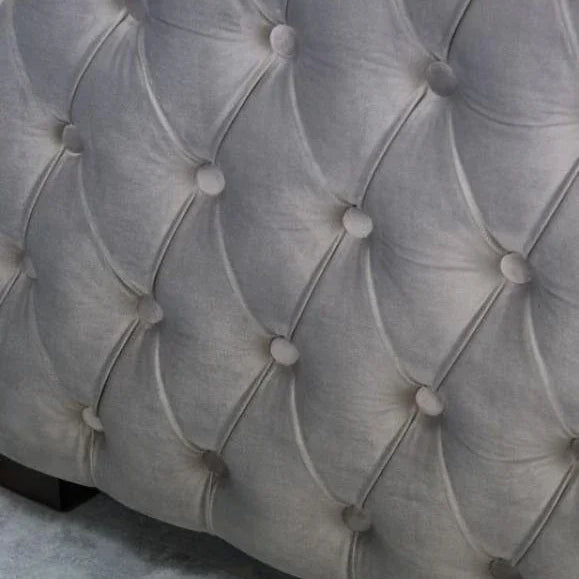 Close up of grey velvet sofa with deep button tufted upholstery