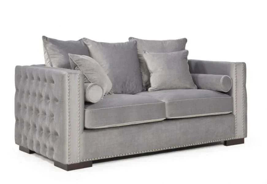 Grey velvet sofa with deep buttoned sides, stud detailing, and plush scatter cushions