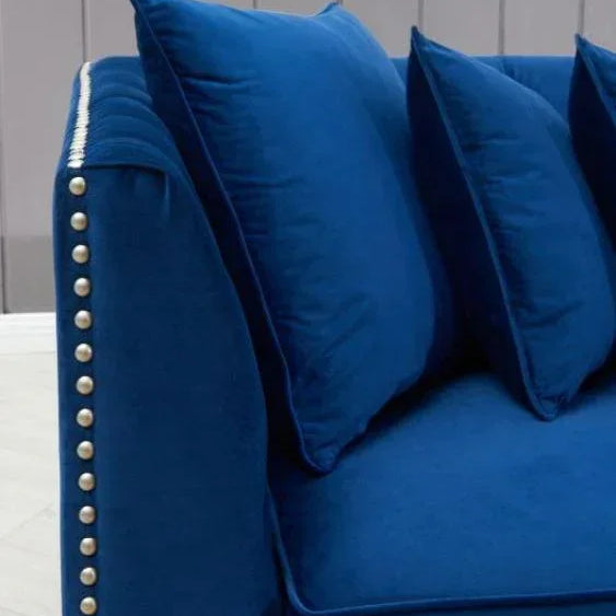 Blue velvet sofa with studded armrest and matching cushions