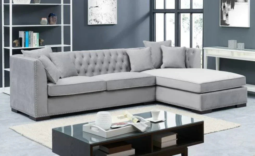 Grey corner sofa with tufted backrest and studded trim in modern living room