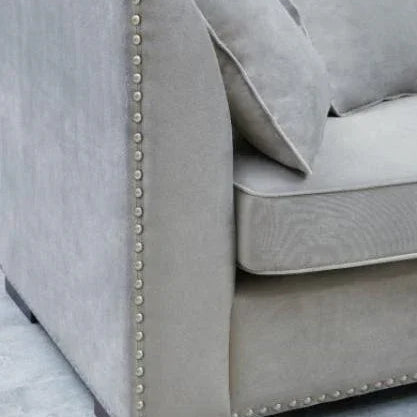 Grey fabric sofa with nailhead trim and matching cushions, close-up of armrest and seat