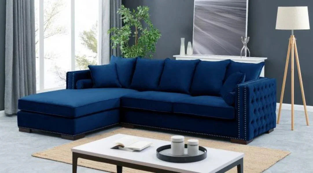 Blue velvet corner sofa with studded arms and cushions in modern living room