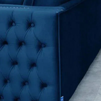 Navy blue velvet sofa with tufted side detail and dark wooden legs on tiled floor