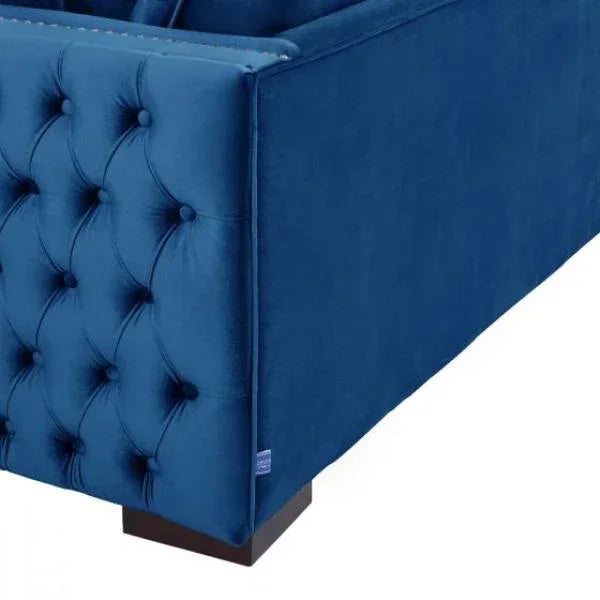 Blue velvet sofa corner with tufted side panel and dark wooden leg