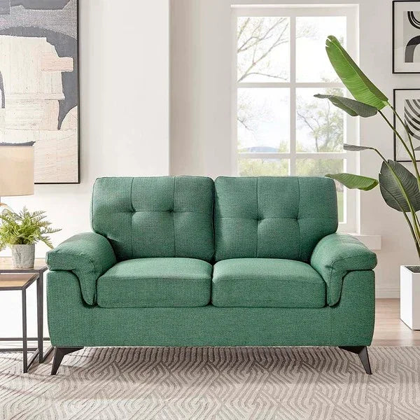 Green fabric sofa with tufted cushions in modern living room with plants and artwork