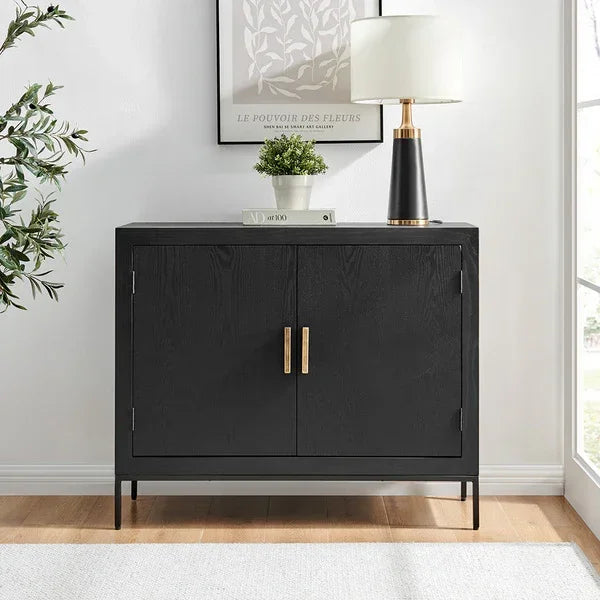 Black wooden sideboard with gold handles styled with lamp, book, and plant