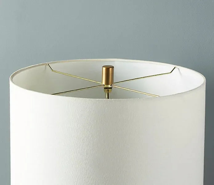 White fabric lampshade with gold metal fitting against a grey wall