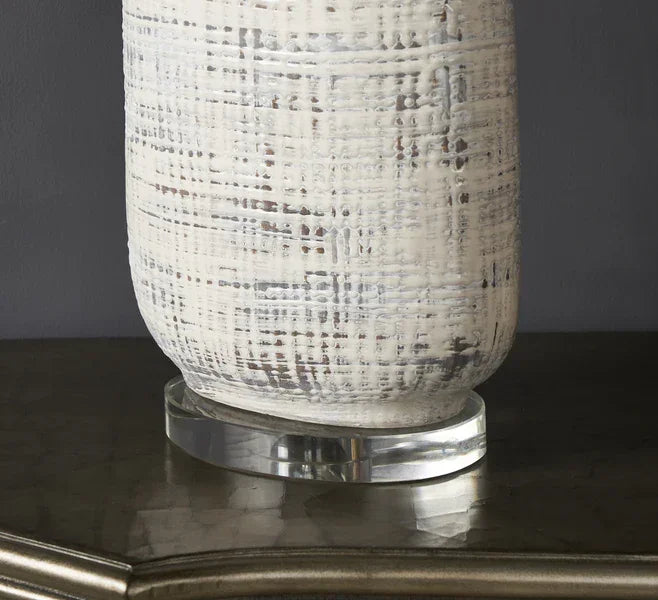 Ceramic textured vase with white and grey pattern on glass base, placed on a table