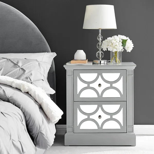 Grey mirrored bedside table with geometric pattern and two drawers beside upholstered bed