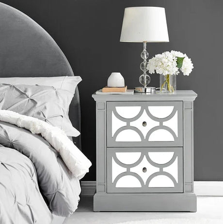 Grey mirrored bedside table with geometric pattern and two drawers beside upholstered bed