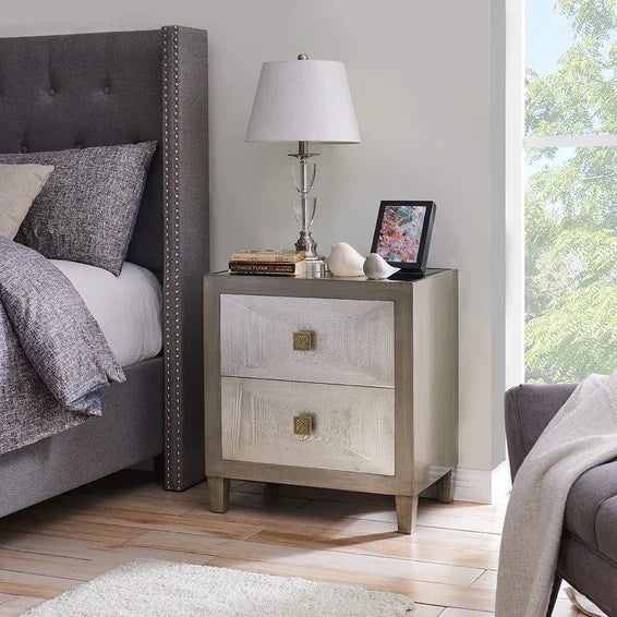 Two drawer bedside table with lamp and decor beside upholstered grey bed