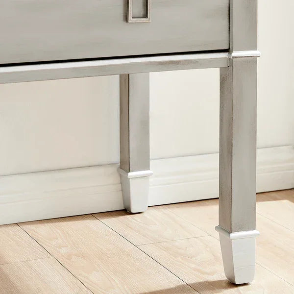 Light grey wooden furniture legs on laminate flooring against white wall
