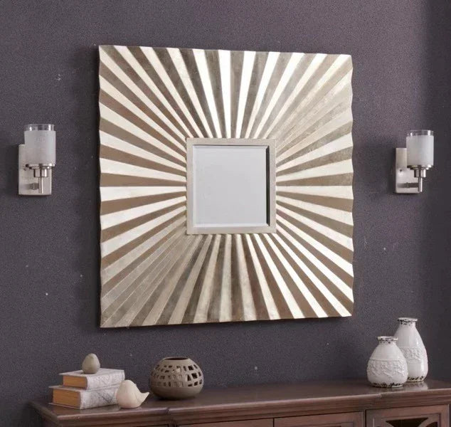 Square sunburst wall mirror with metallic frame above wooden console table