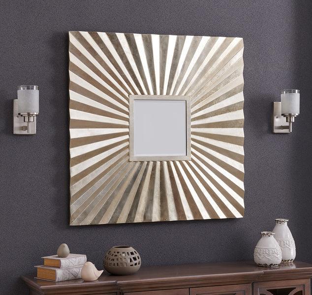 Square wall mirror with sunburst metallic frame above wooden console table and decor vases