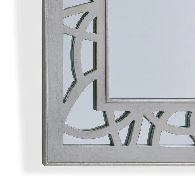 Silver decorative wall mirror with geometric pattern frame close-up