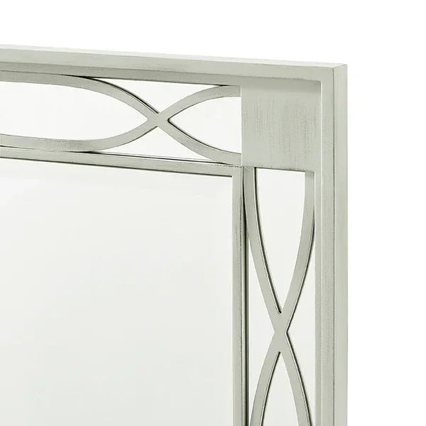 Silver metal framed mirror with geometric cut-out pattern, close-up of top corner
