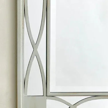 Rectangular wall mirror with silver frame and geometric metallic detailing in corner view
