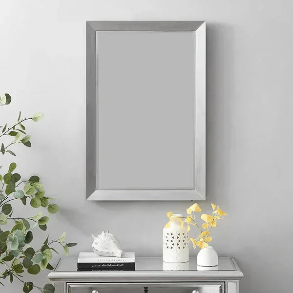 Rectangular silver wall mirror above mirrored console table with decorative vases