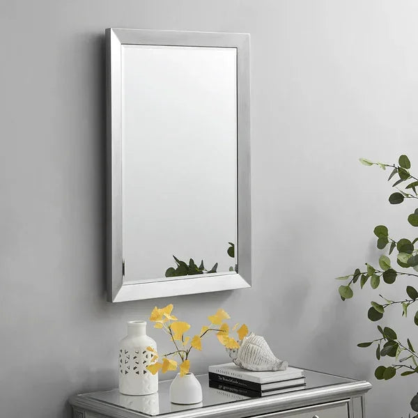 Rectangular wall mirror with silver frame above mirrored console table and decorative vases