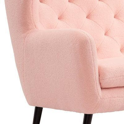 Light pink accent chair with tufted upholstery and black wooden legs, side angle view