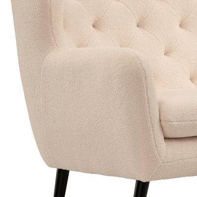 Cream fabric sofa with tufted backrest and black tapered legs, close-up of arm and seat