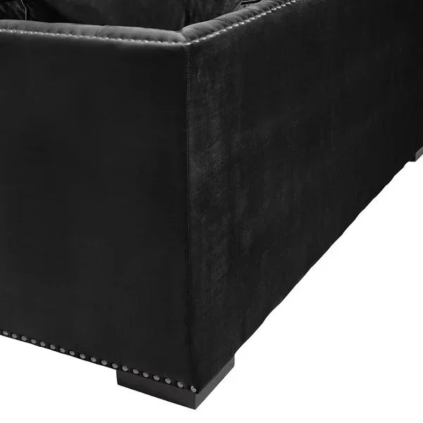 Black velvet sofa corner detail with nailhead trim and low wooden feet