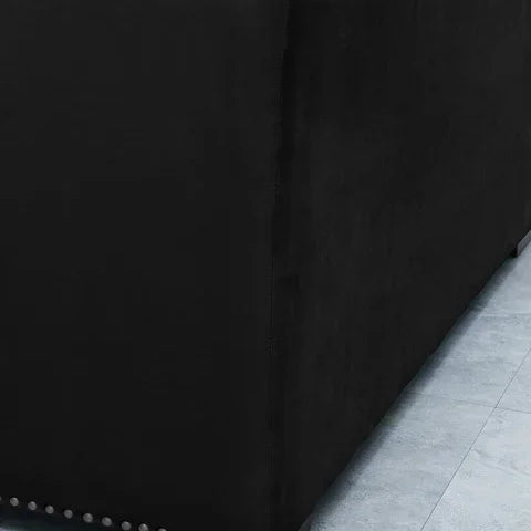 Black fabric sofa corner with silver stud detailing and wooden legs on tiled floor