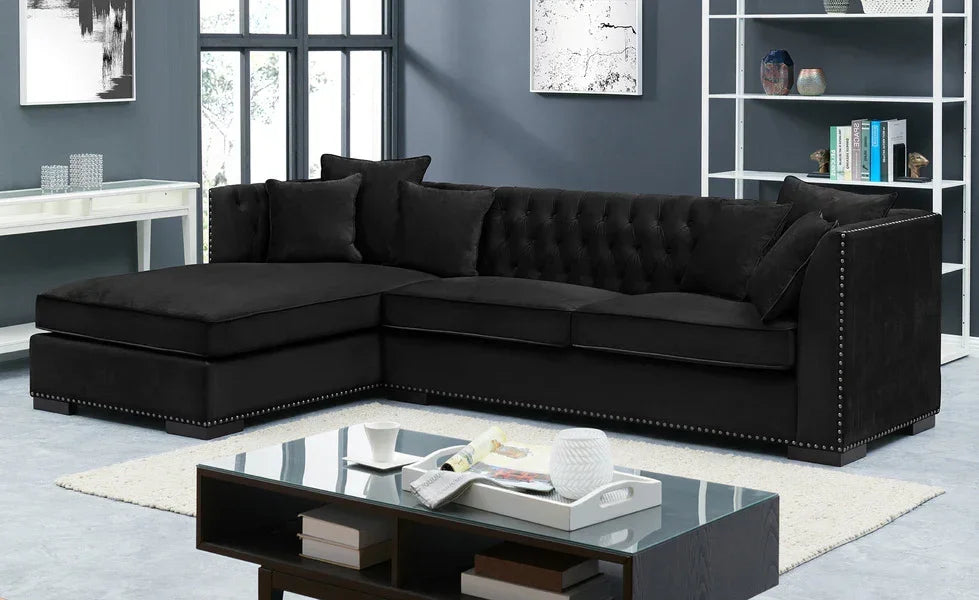 Black corner sofa with tufted back and nailhead trim in modern living room setting
