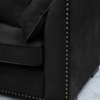 Black fabric sofa with nailhead trim and scatter cushions on light carpet
