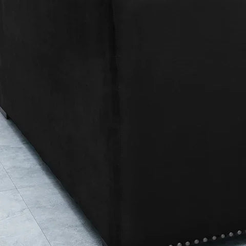 Black fabric sofa with studded trim and wooden legs on tiled floor