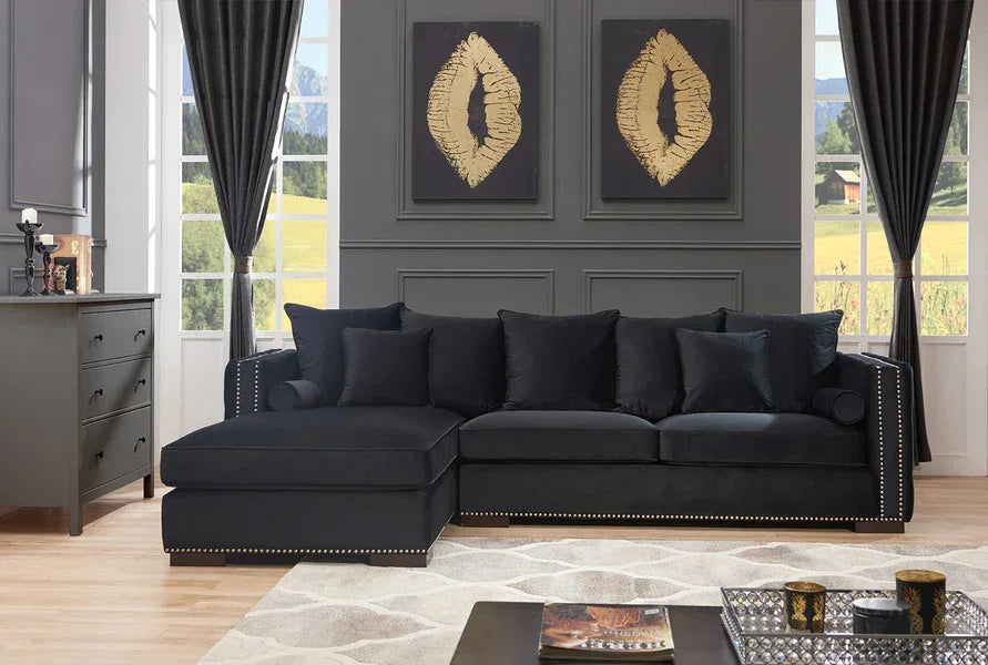 Black corner sofa with studded arms and velvet cushions in a modern living room